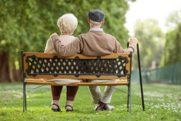 Ein älteres Paar sitzt auf einer Parkbank.